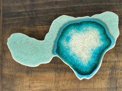 Geode-like ceramic dish with blue and green interior on a wooden surface